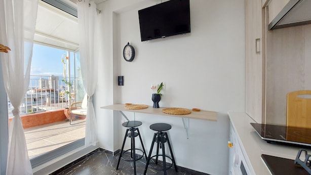 Et moderne køkken med fjernsyn, et ur og en balkon med udsigt over byen.