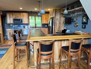 A modern kitchen with wooden cabinetry, a central island with bar stools, and pendant lighting.