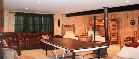 Una habitación con mesa de ping pong, sofá de cuero y pared de madera.
