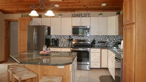 A kitchen with a central island, stainless steel appliances, and wooden cabinetry. - Welcome to Howe Hill Retreat! (Great Valley)