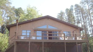 A two-story wooden cabin with a balcony on the upper floor, surrounded by trees. - Welcome to Howe Hill Retreat! (Great Valley)