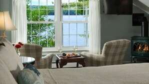 A cozy room with a large window, a fireplace, a television, and a dining area with a table set for two. - Wolf Cove Inn (Poland)
