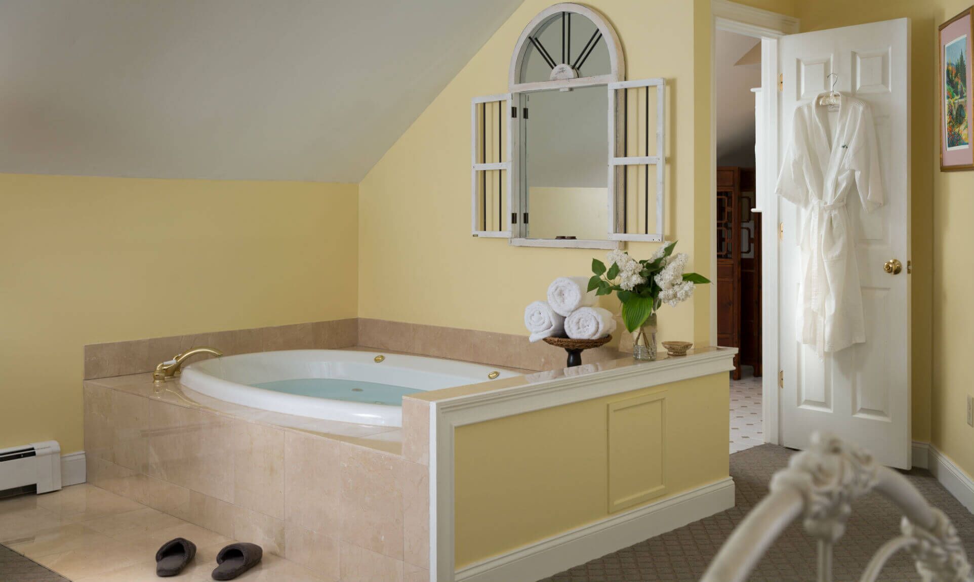 Ein Badezimmer mit einer großen Badewanne, einem Spiegel und einer Tür zu einem anderen Raum.