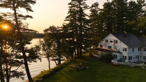 A two-story house with a large porch and a view of a lake. - Wolf Cove Inn (Poland)