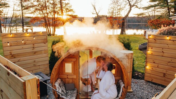 A wooden cabin with a circular entrance, a bench, and a small table. - Wolf Cove Inn (Poland)