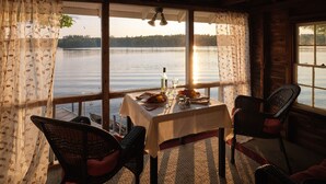 A dining area with a table set for two, overlooking a lake. - Wolf Cove Inn (Poland)