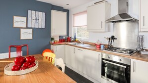 Une cuisine moderne avec des armoires blanches, une hotte de cuisinière en acier inoxydable et un plan de travail en bois.