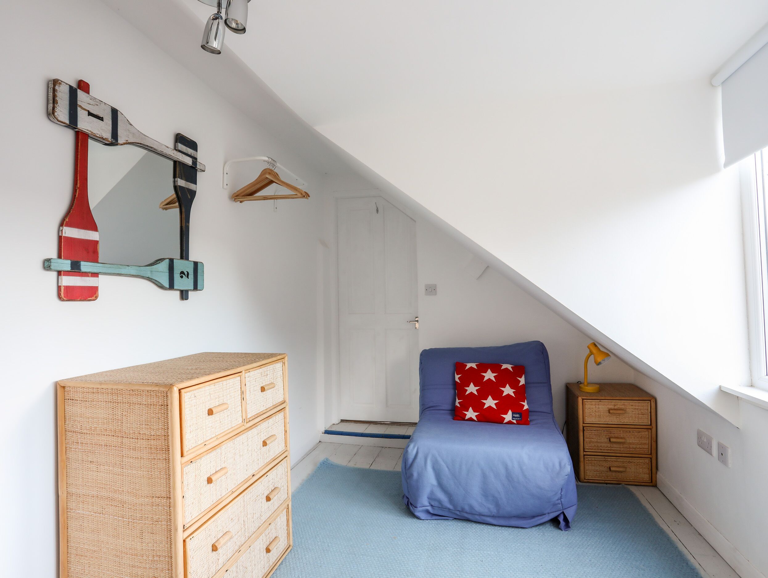 A child's room with a bunk bed, a dresser, a hanging coat rack, and a ceiling fan.