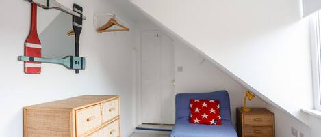A child's room with a bunk bed, a dresser, a hanging coat rack, and a ceiling fan.