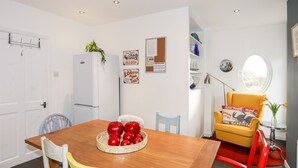 Un coin repas comprenant une table en bois, des chaises, un réfrigérateur et des éléments de décoration murale.
