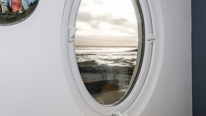 Une fenêtre donnant sur une plage et une illustration d’époque.