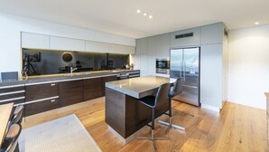 A modern kitchen with a central island, dark cabinetry, stainless steel appliances, and a minimalist design. - Lakefront Apartment close to town (Wānaka)