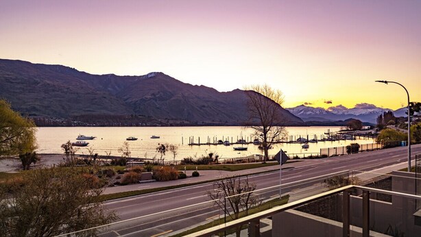 A waterfront road with a marina, boats, and mountains in the background. - Lakefront Apartment close to town (Wānaka)