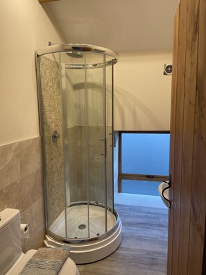 A modern bathroom with a glass-enclosed shower, a toilet, and a wooden floor. - Rookery Barn in the Outskirts of Darley (Harrogate)