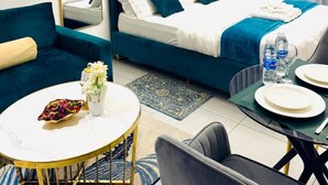 A modern hotel room with a bed, a sofa, a round dining table, and a chair.