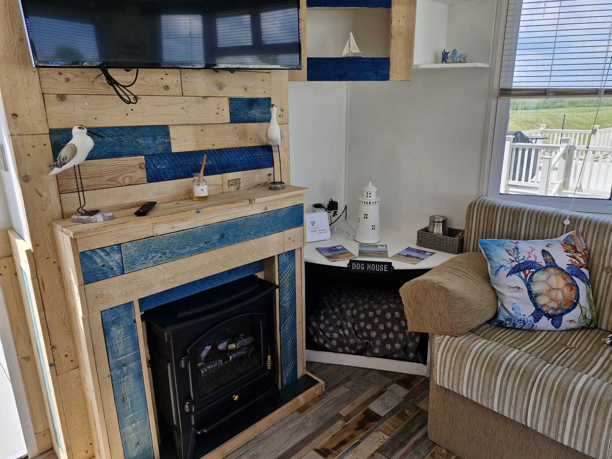 A cozy living room with a fireplace, a television mounted above it, and a comfortable couch with a decorative pillow.