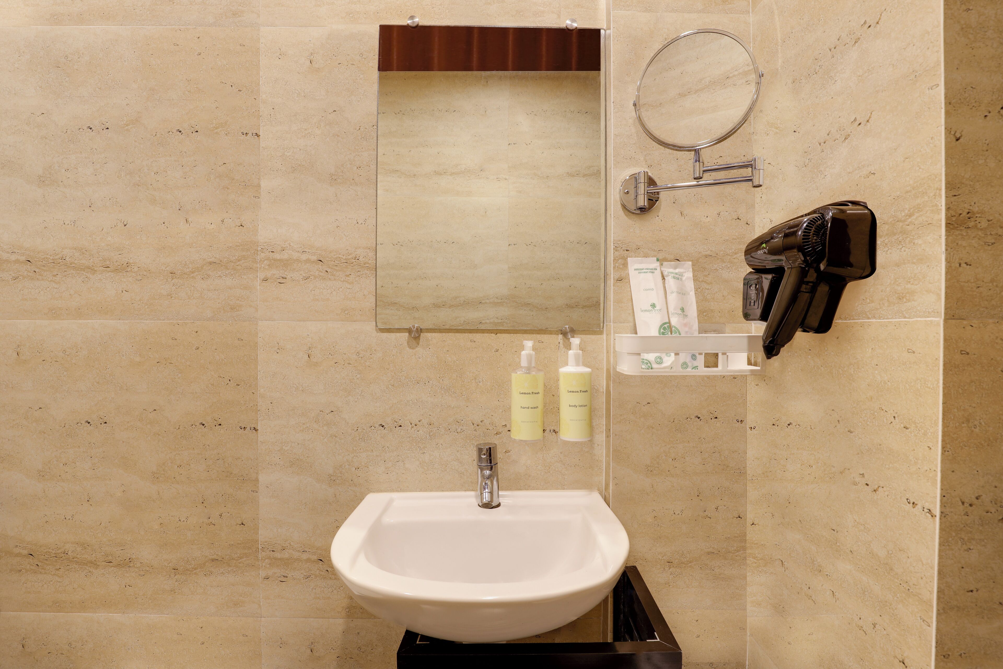 Une salle de bain équipée d’un lavabo, d’un miroir, d’un porte-serviettes et d’un sèche-cheveux.