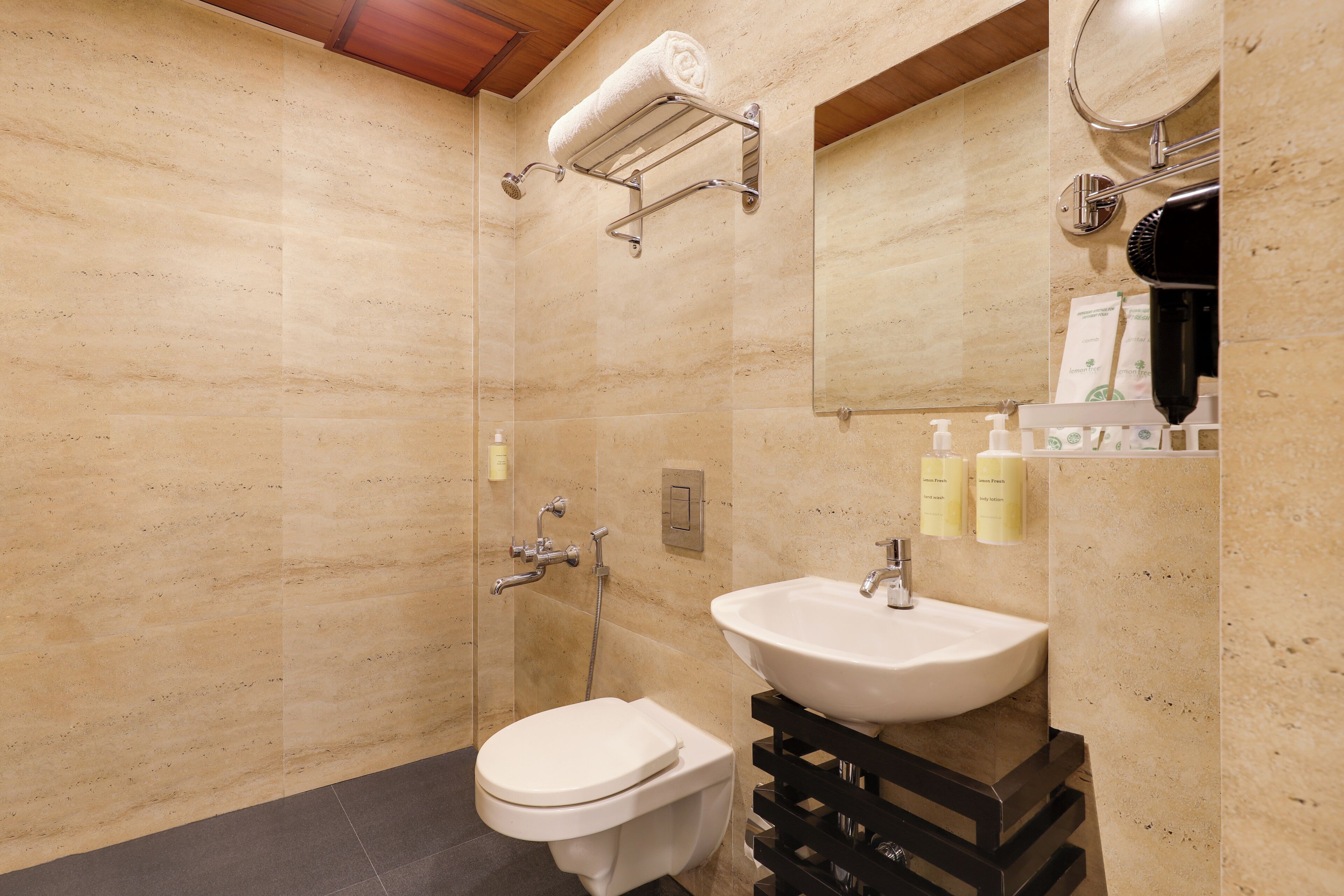 A bathroom with a shower, toilet, sink, and a towel rack.