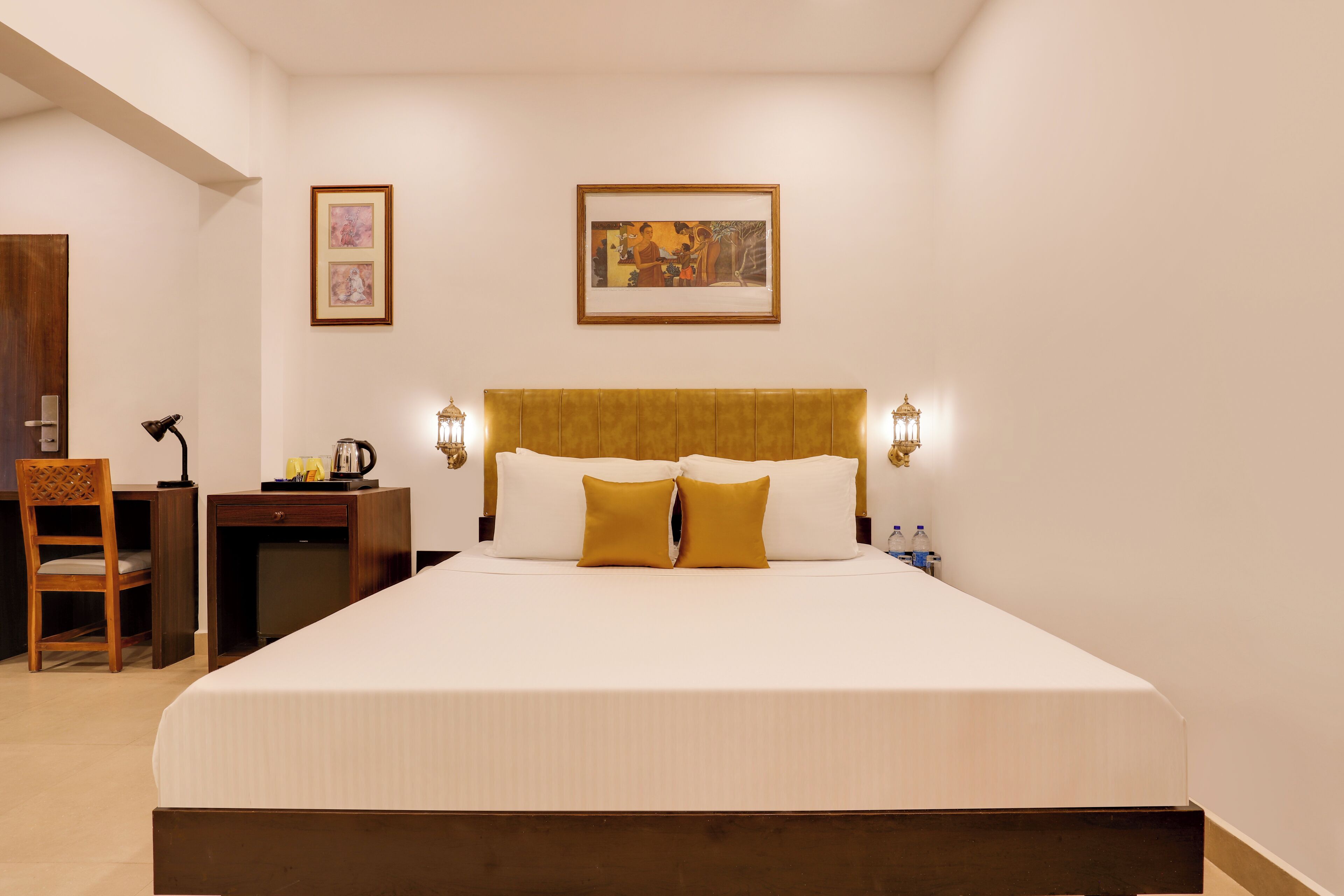 Hotelkamer met een groot bed, twee nachtkastjes, een bureau, een stoel en twee wandlampen.