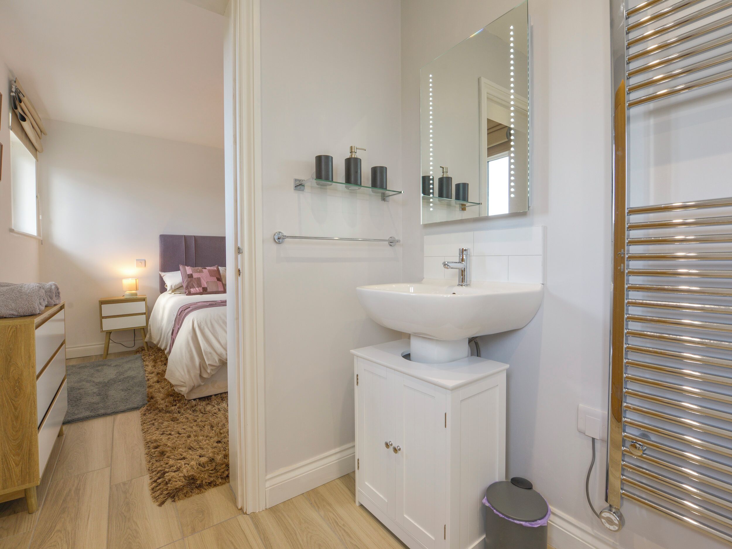 A modern bathroom with a white sink, mirror, and storage cabinets.