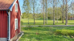 Een rood gebouw met een pannendak, een gazon en bomen op de achtergrond.