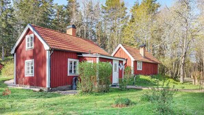 Een rode houten woning met schuin dak, schoorsteen en klein terras.