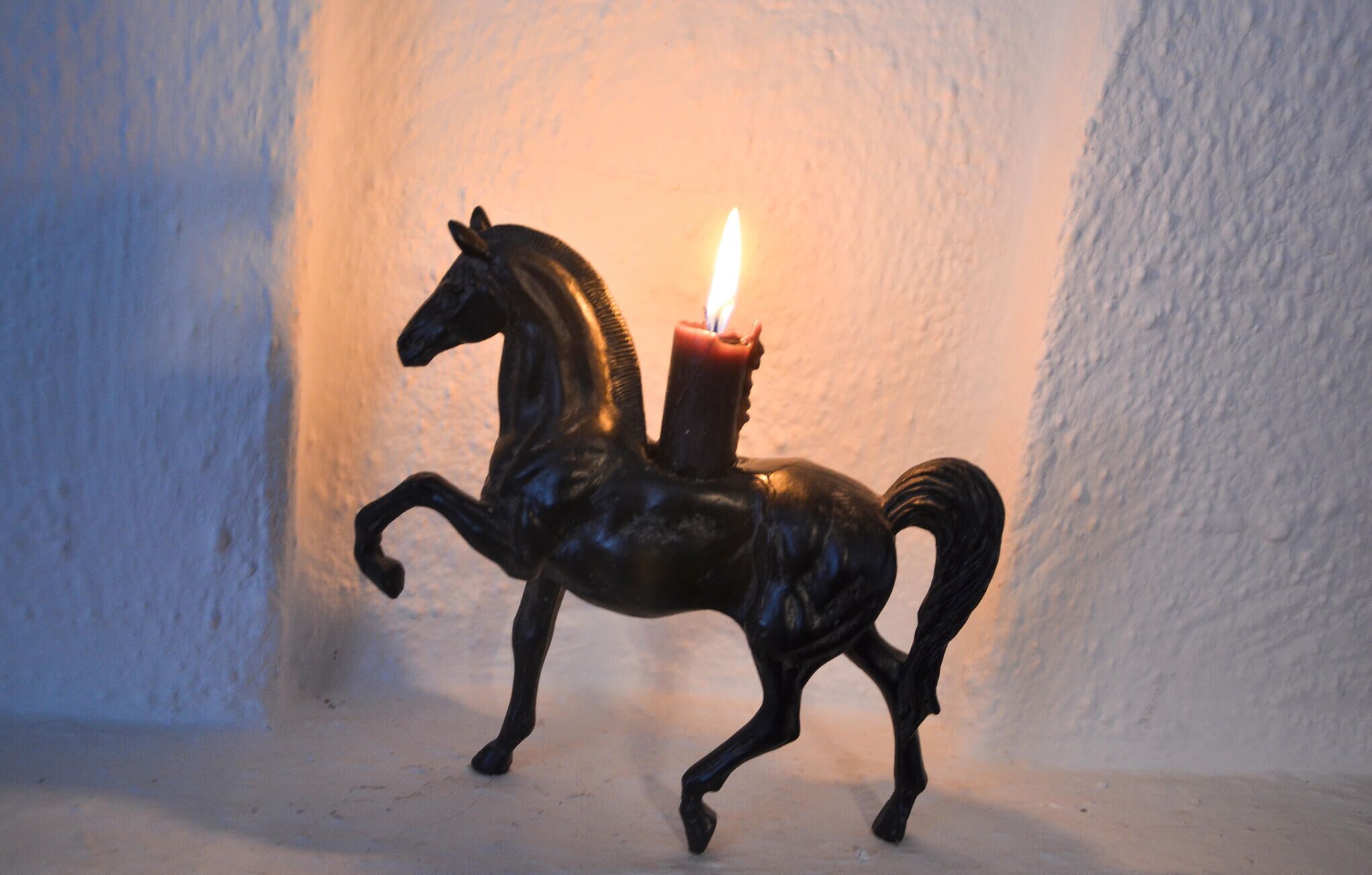 Eine Kerze in Form eines Pferdes mit einer brennenden Flamme.
