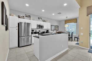Enjoy meals in the well-lit kitchen with a central island, white cabinetry, and stainless steel appliances.