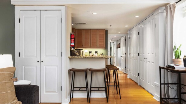 Une cuisine moderne avec des meubles blancs, un îlot central doté de tabourets et un plancher en bois.