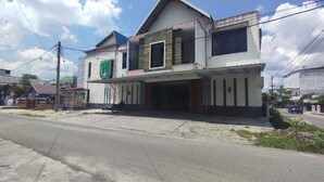 A two-story building with a flat roof and a balcony on the second floor.