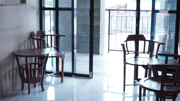 A modern interior with wooden tables and chairs, large windows, and a glass door leading outside.