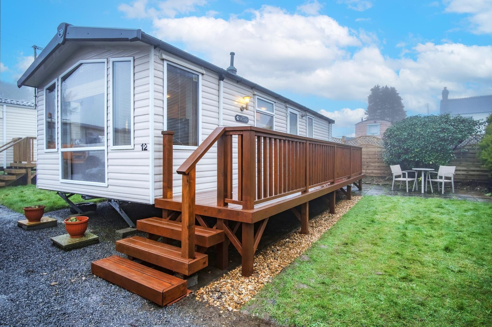Une maison mobile dotée d’une terrasse en bois et d’un escalier menant à l’entrée.