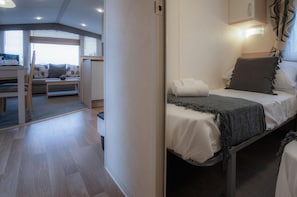 Une chambre moderne avec un lit, une table de chevet et une vue sur un espace de vie comprenant un canapé et une table.