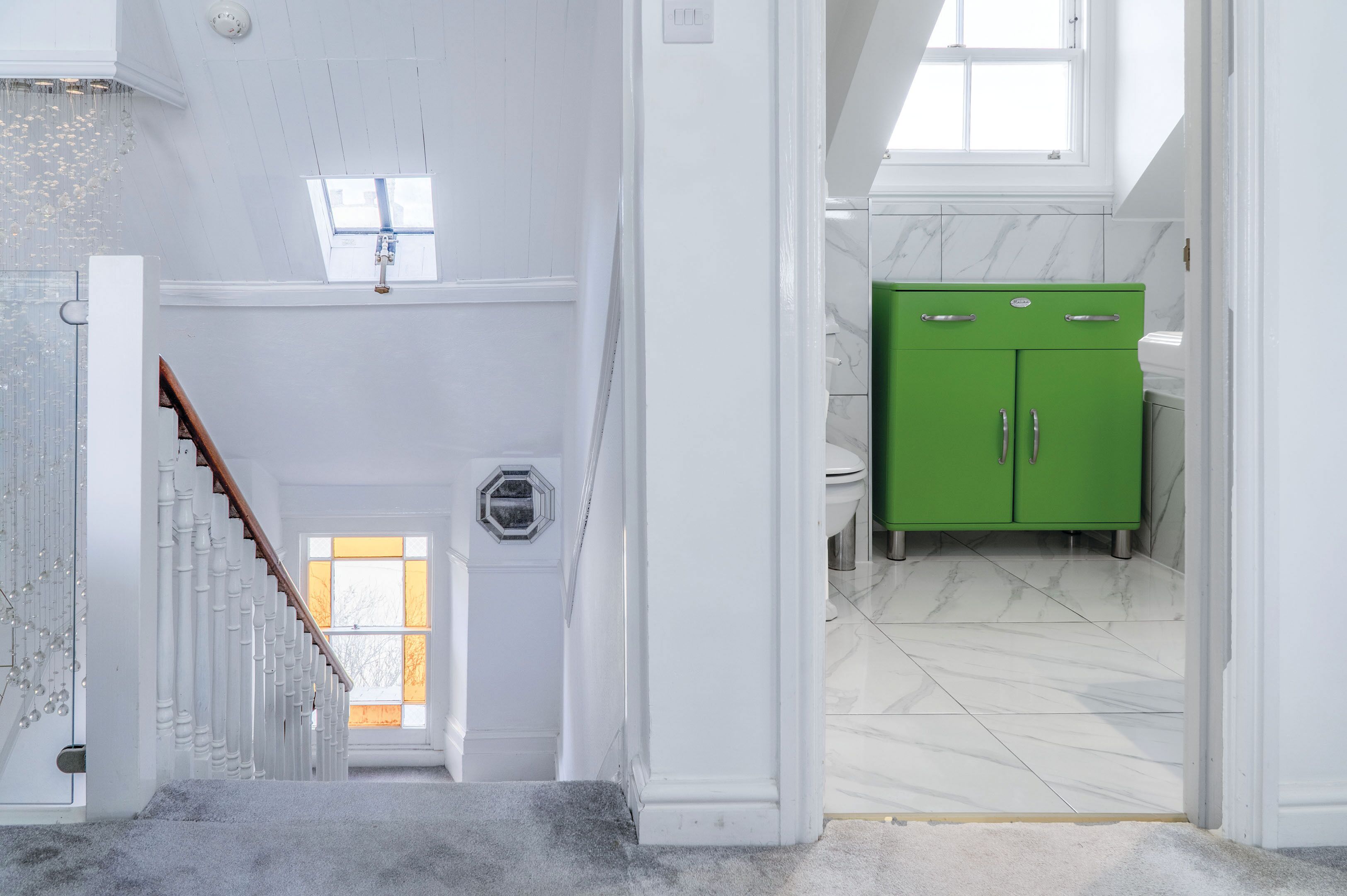 Een trap die leidt naar een kamer met een groen kastje en een raam.