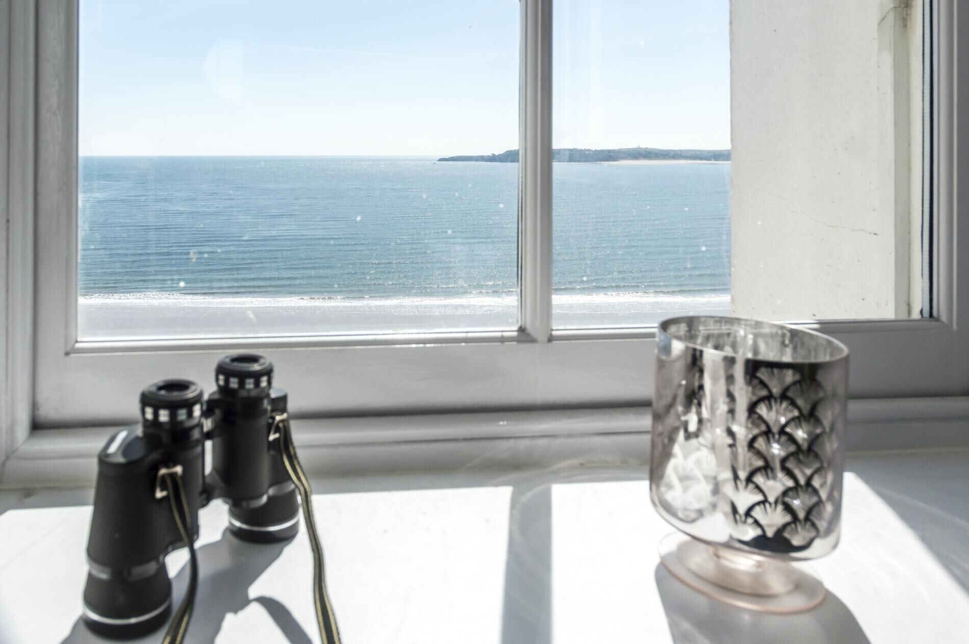A window with binoculars and a metal container on a windowsill.