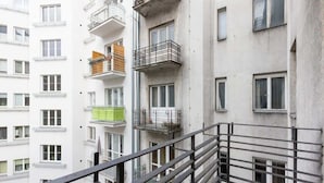 A multi-story residential building with balconies, a metal railing, and a brick ground floor.