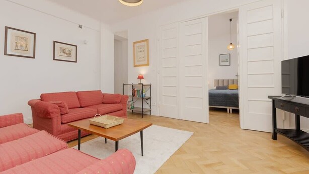 A compact living space with a red sofa, a small wooden table, and a TV on a stand.