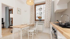 A modern kitchen with white cabinetry, a wooden countertop, and a window with patterned curtains.