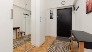 A modern hotel room with a large mirror, a black door, a small table, and a patterned rug.