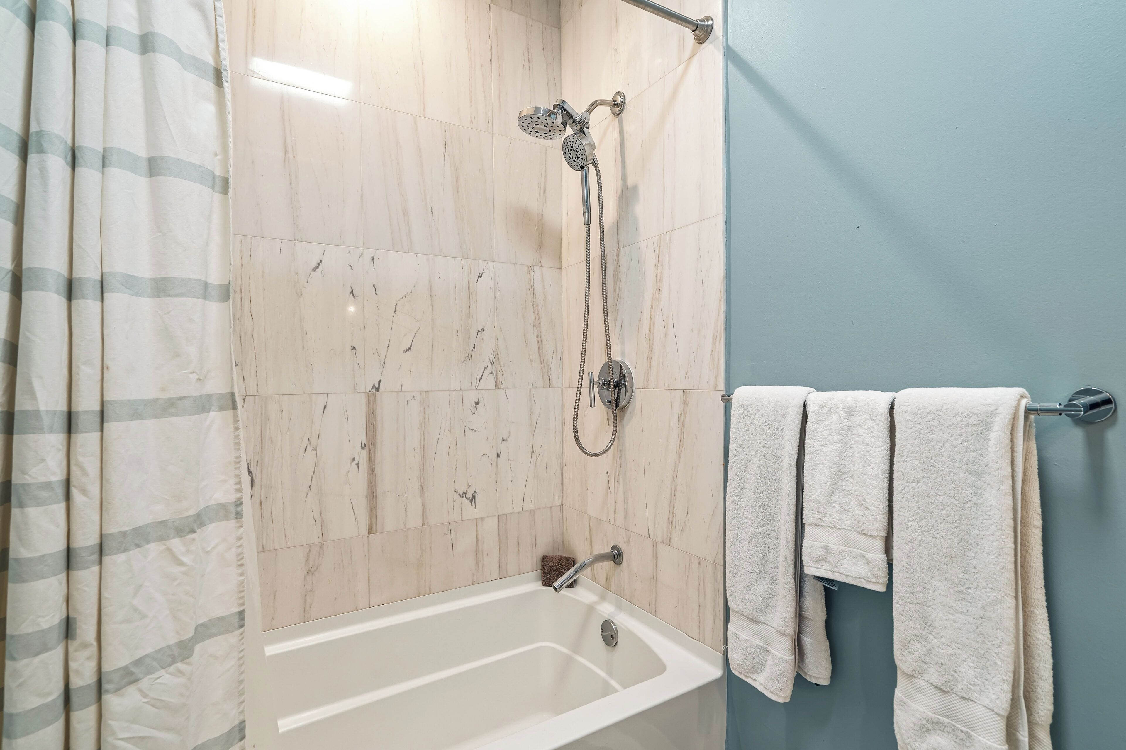 Une salle de bain avec une baignoire, une douche et un porte-serviettes.