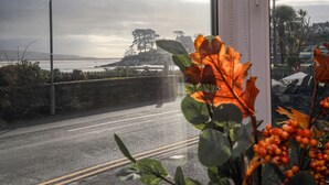 A coastal road with a stone wall and a view of the sea and hills. - Gweldon - Anchor Deck (Porthmadog)