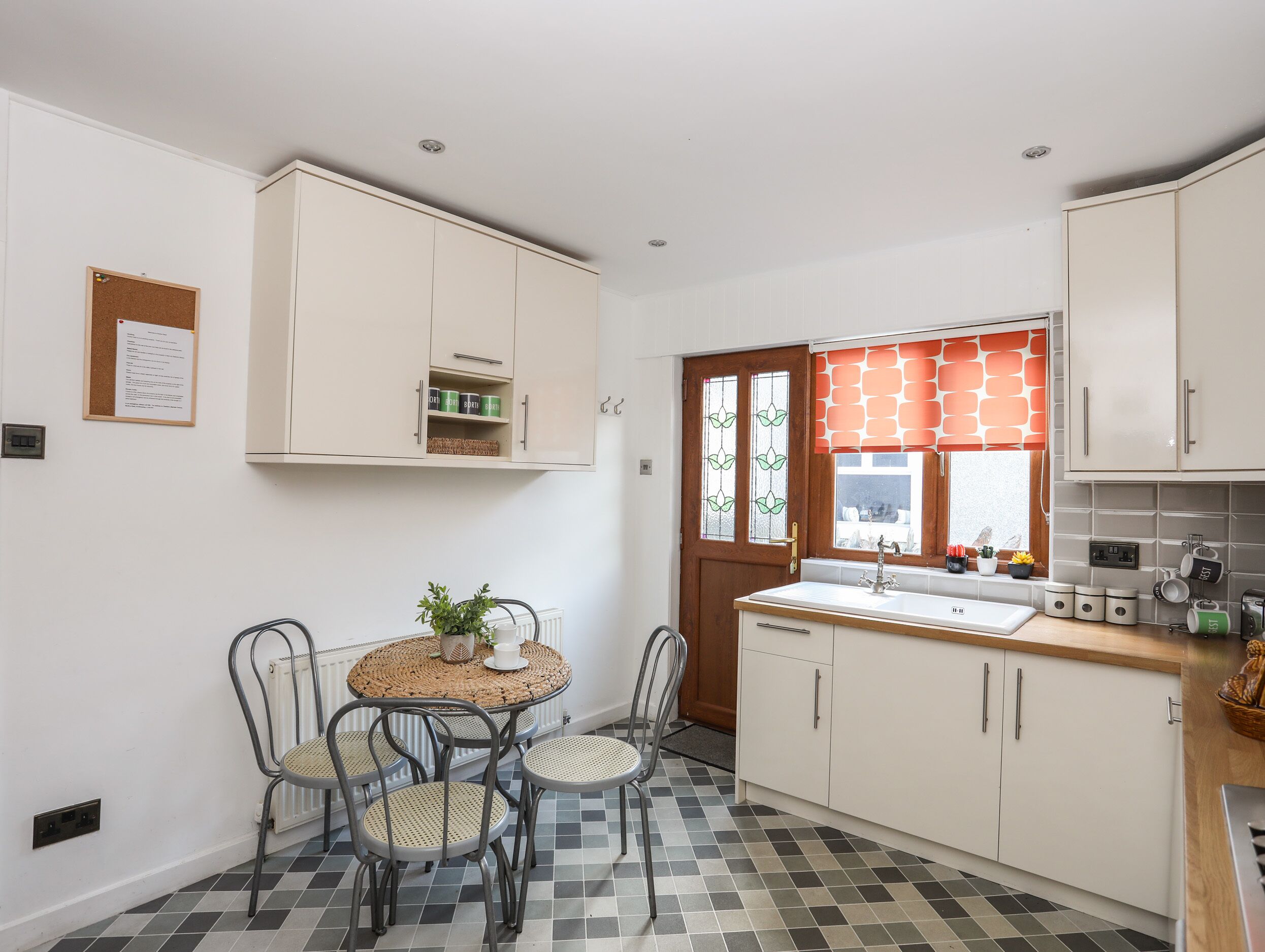 A compact kitchen with a dining area, featuring a round table with chairs, a built-in sink, and storage cabinets.