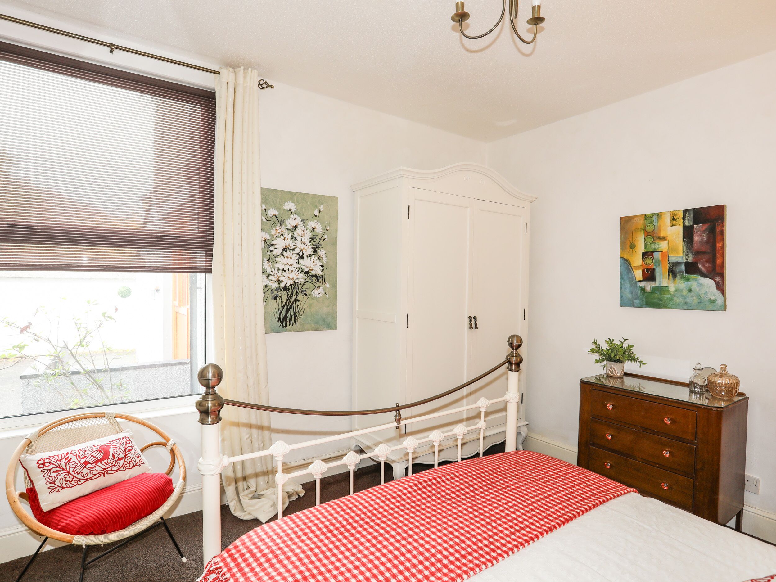 Ein Schlafzimmer mit Bett, Kleiderschrank, Stuhl und einem Bild an der Wand.