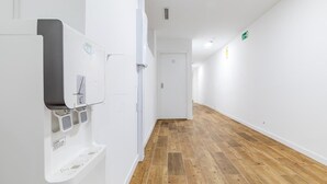A modern hallway with a water dispenser, a door at the end, and a wooden floor. - AYZ Luis Cabrera-Auto check-in property (Madrid)