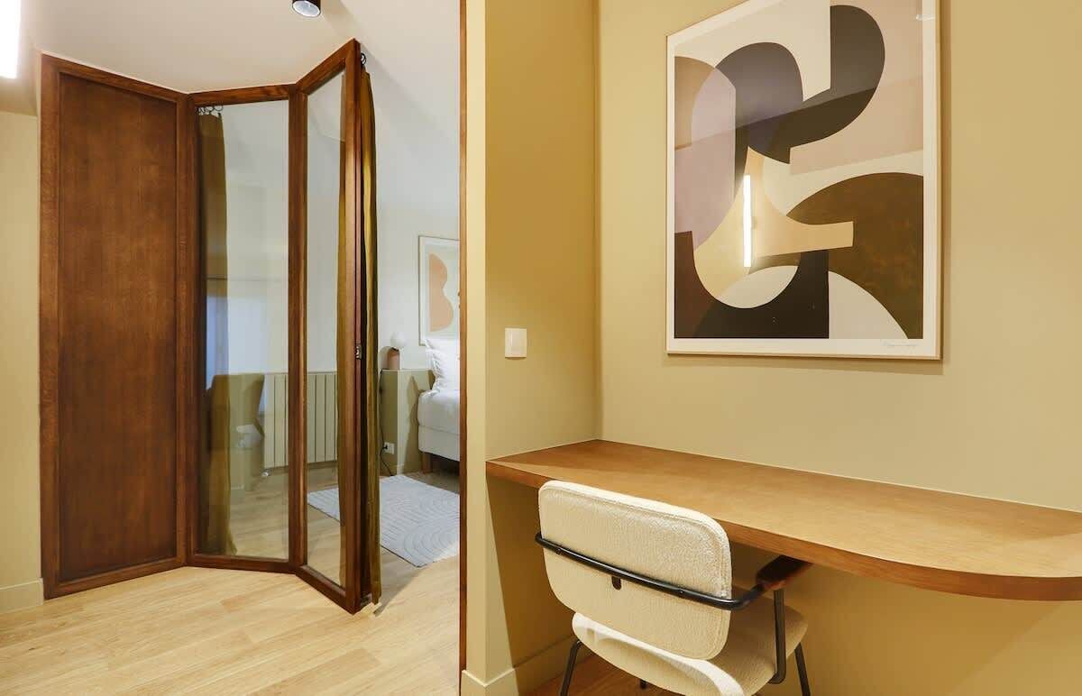Una habitación con un escritorio de madera, una silla y una obra de arte abstracta de gran tamaño en la pared.