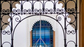 A room with a decorative metal gate, a hanging lantern, and a window with blue curtains. - Riad Tafoukt Palace (Fes)