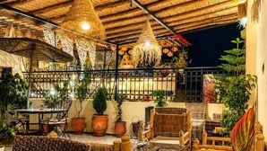 An outdoor patio area with wicker furniture, potted plants, and hanging light fixtures. - Riad Tafoukt Palace (Fes)