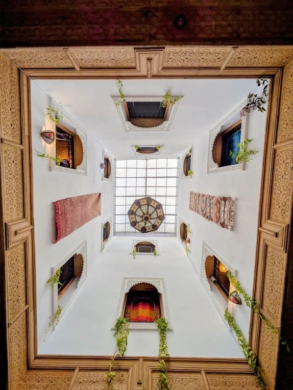 A room with a central skylight, decorative ceiling, and patterned walls.