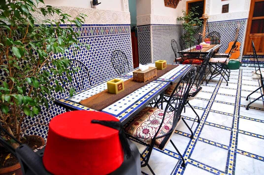 Een eethoek met een lange tafel, stoelen en een rood voorwerp op de vloer.