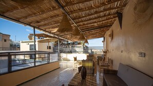 An outdoor seating area with wicker furniture, a glass balustrade, and a view of the sea. - Riad Tafoukt Palace (Fes)